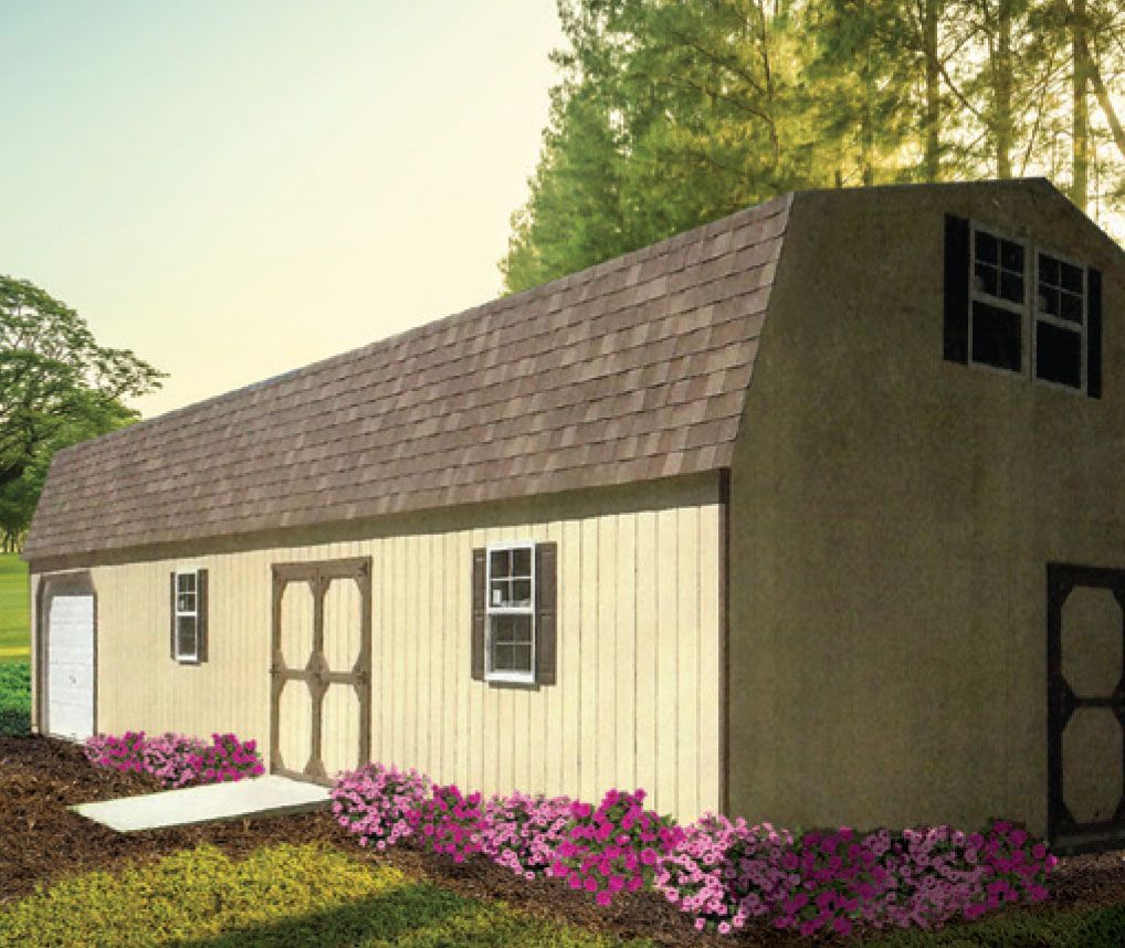 Tan barn-style shed with brown roof, black shutters, and pink flowers in front.