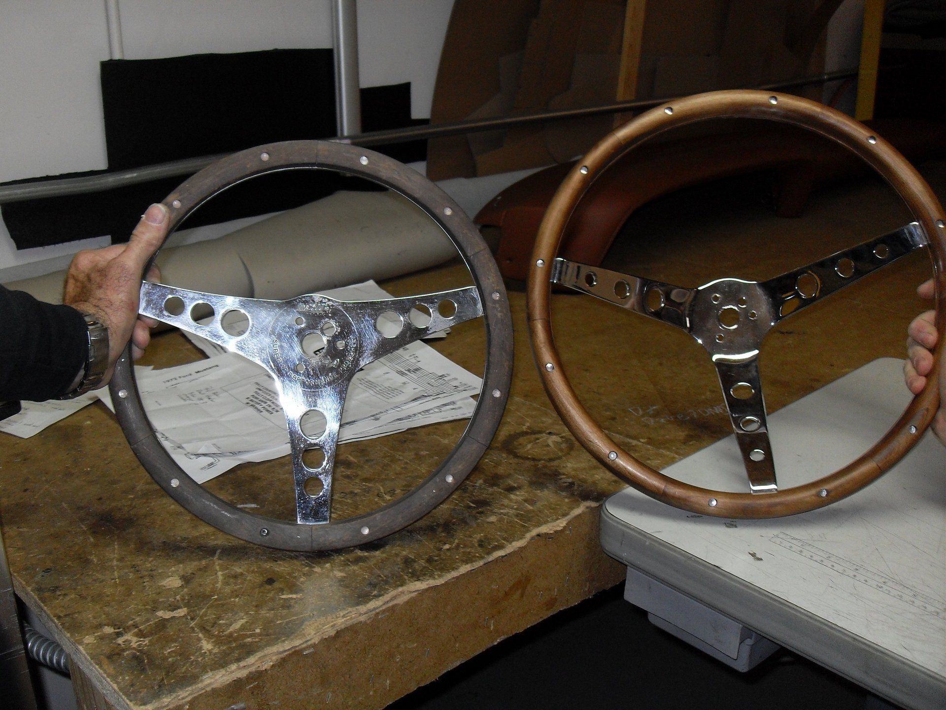 A person is holding a steering wheel next to another steering wheel.