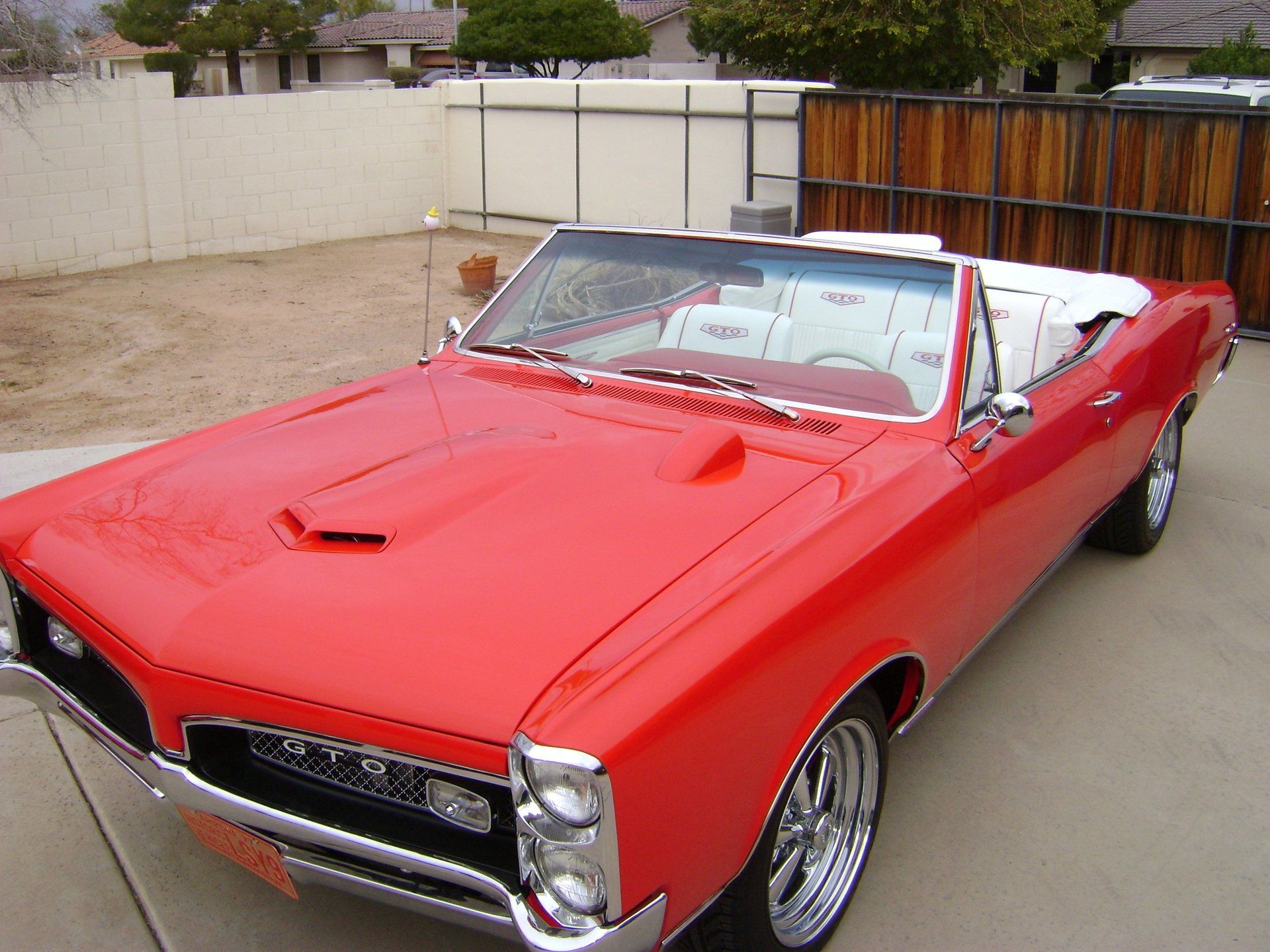 A red car with a white top is parked in a driveway.