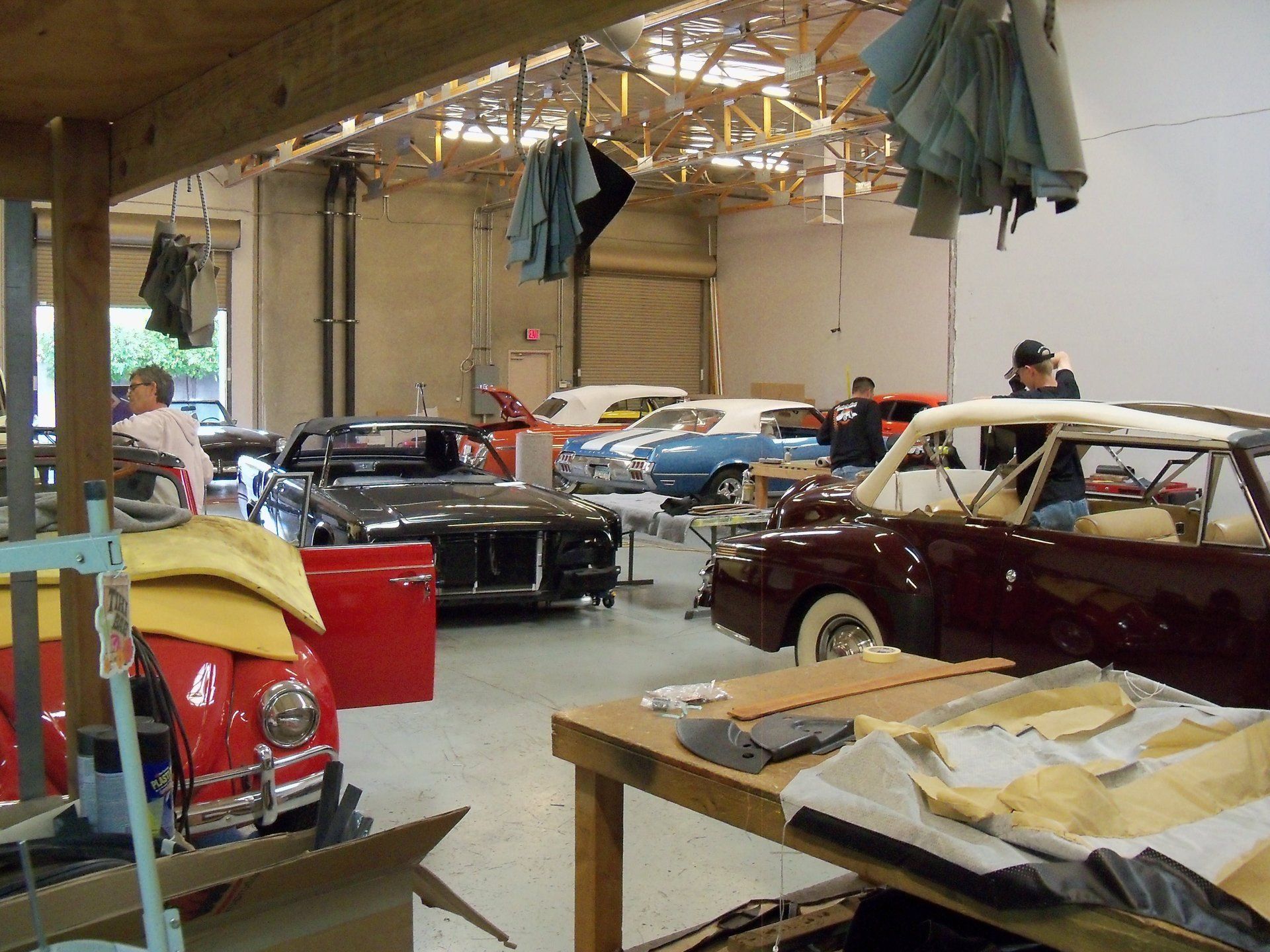 A man in a black shirt with a vans' logo on the back is working on a table.