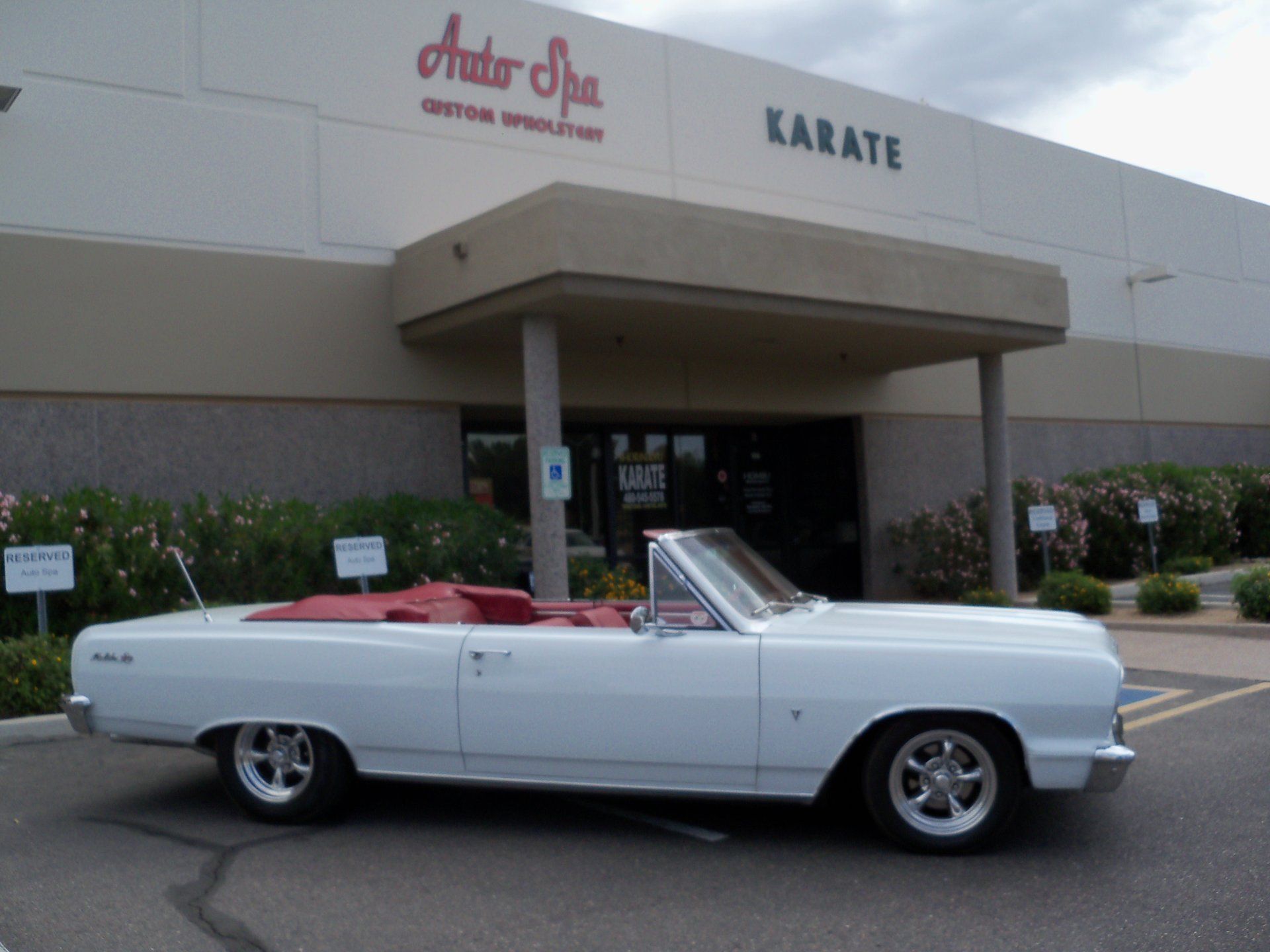 A white convertible is parked in front of an auto spa.