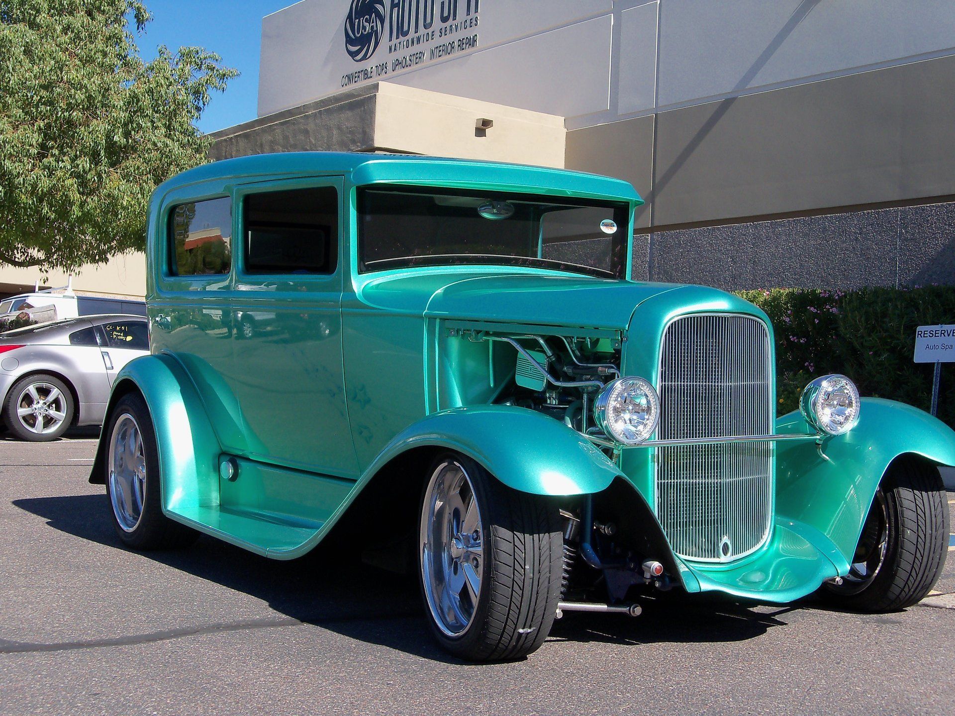 A green car is parked in front of a building that says ' kingsway ' on it