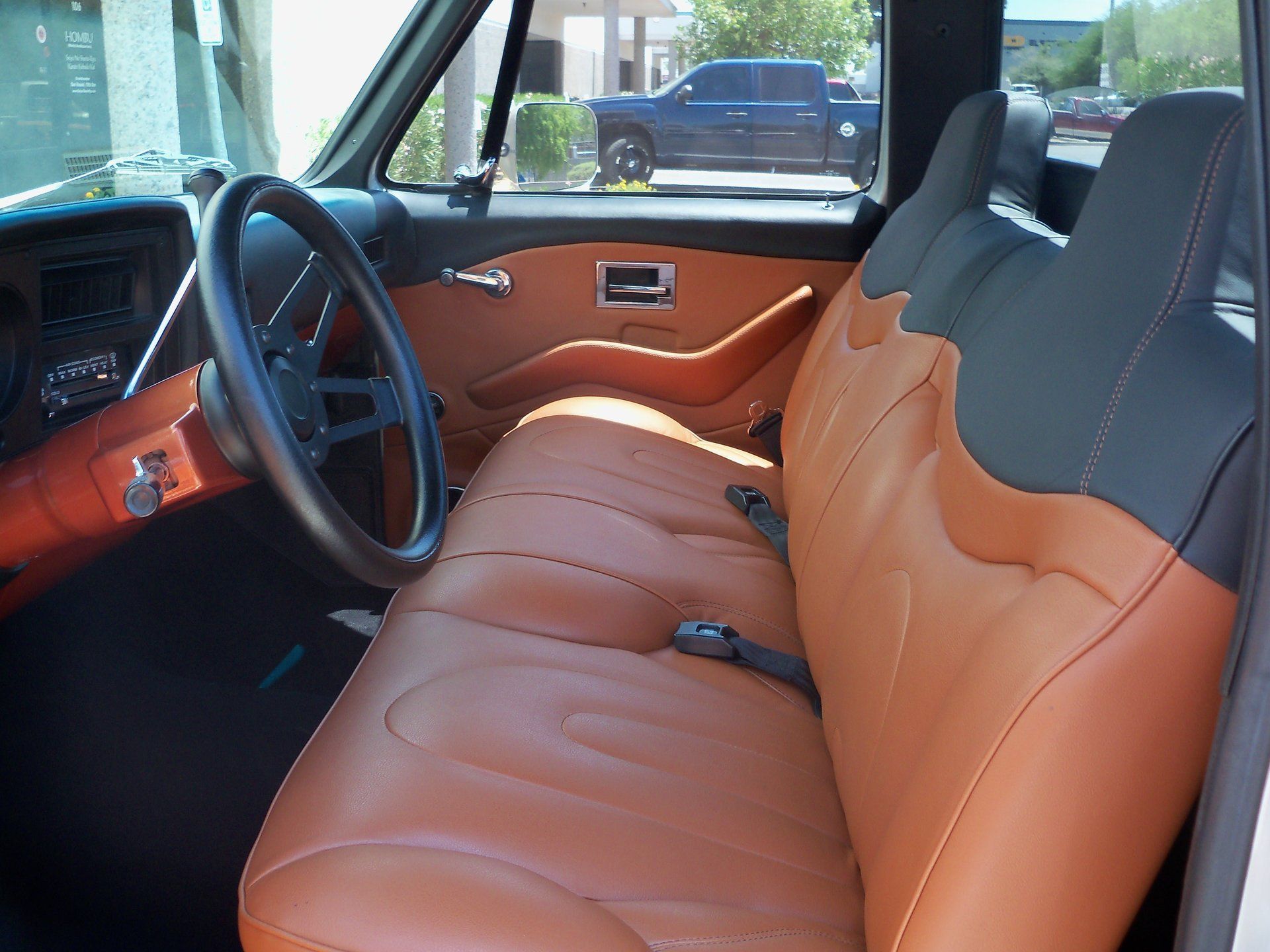 The interior of a truck with brown leather seats and a black steering wheel.