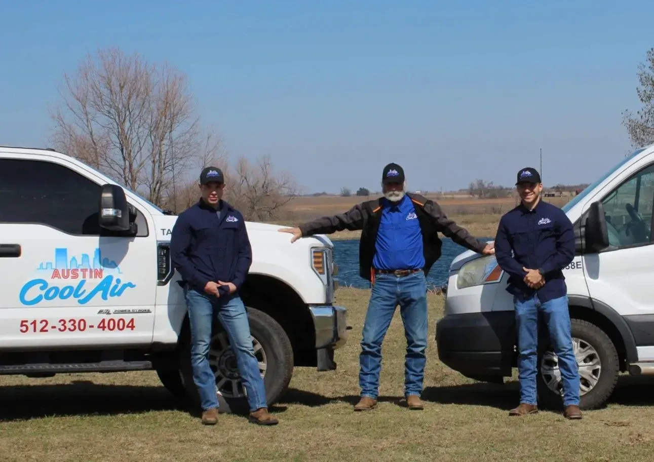 Three men in uniform stand next to white work trucks; company logos on vehicles.