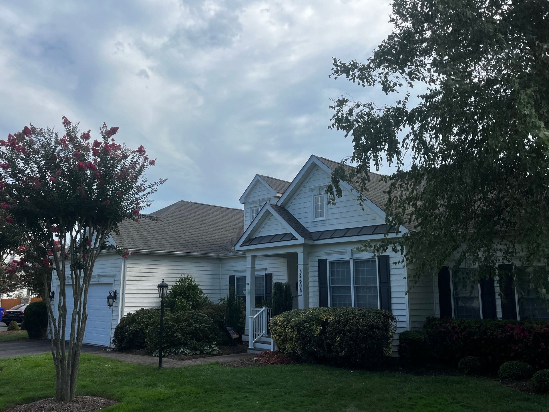 A white house with a gray roof and white shutters.