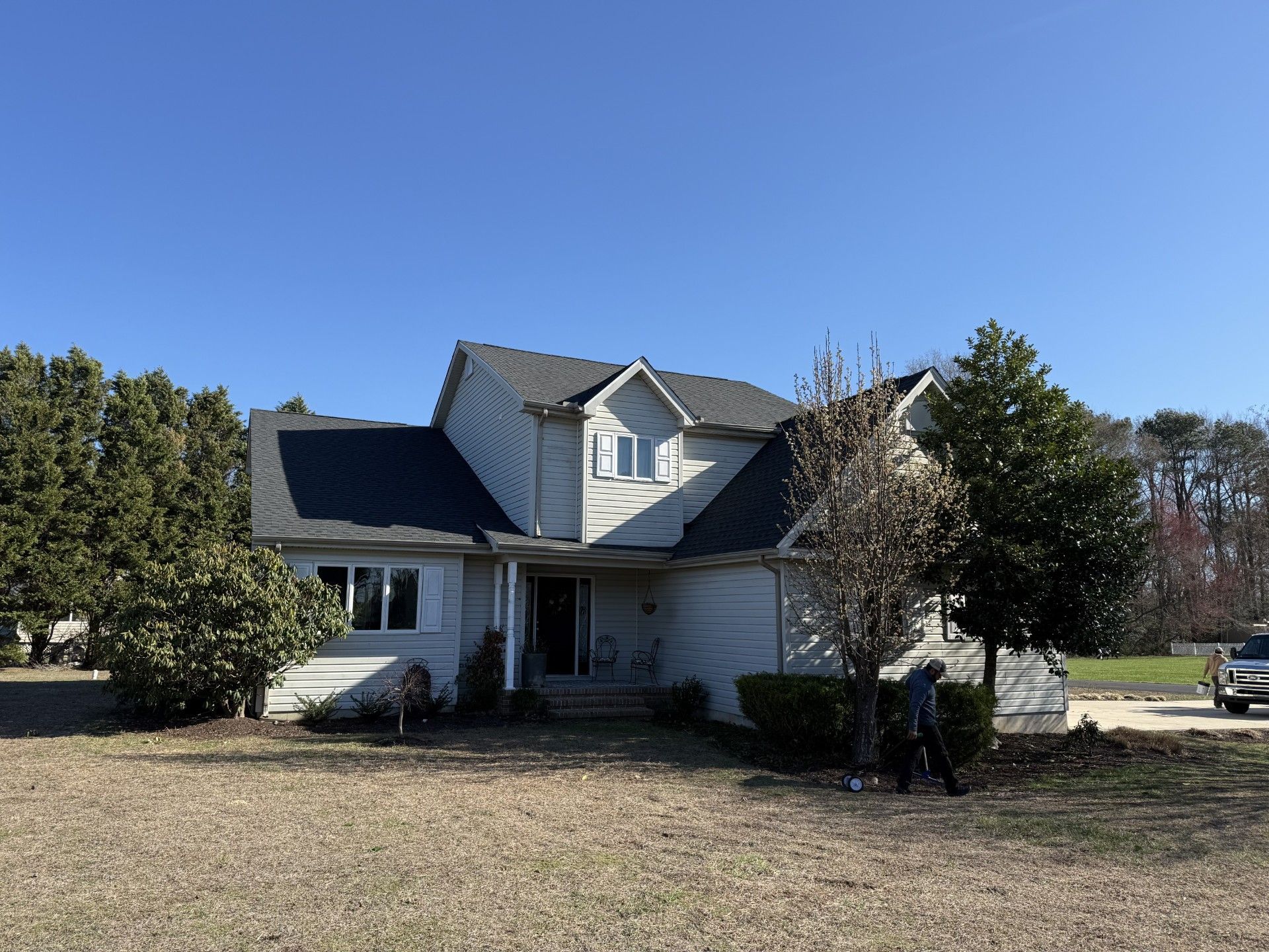 A white house with a gray roof and solar panels on the roof.