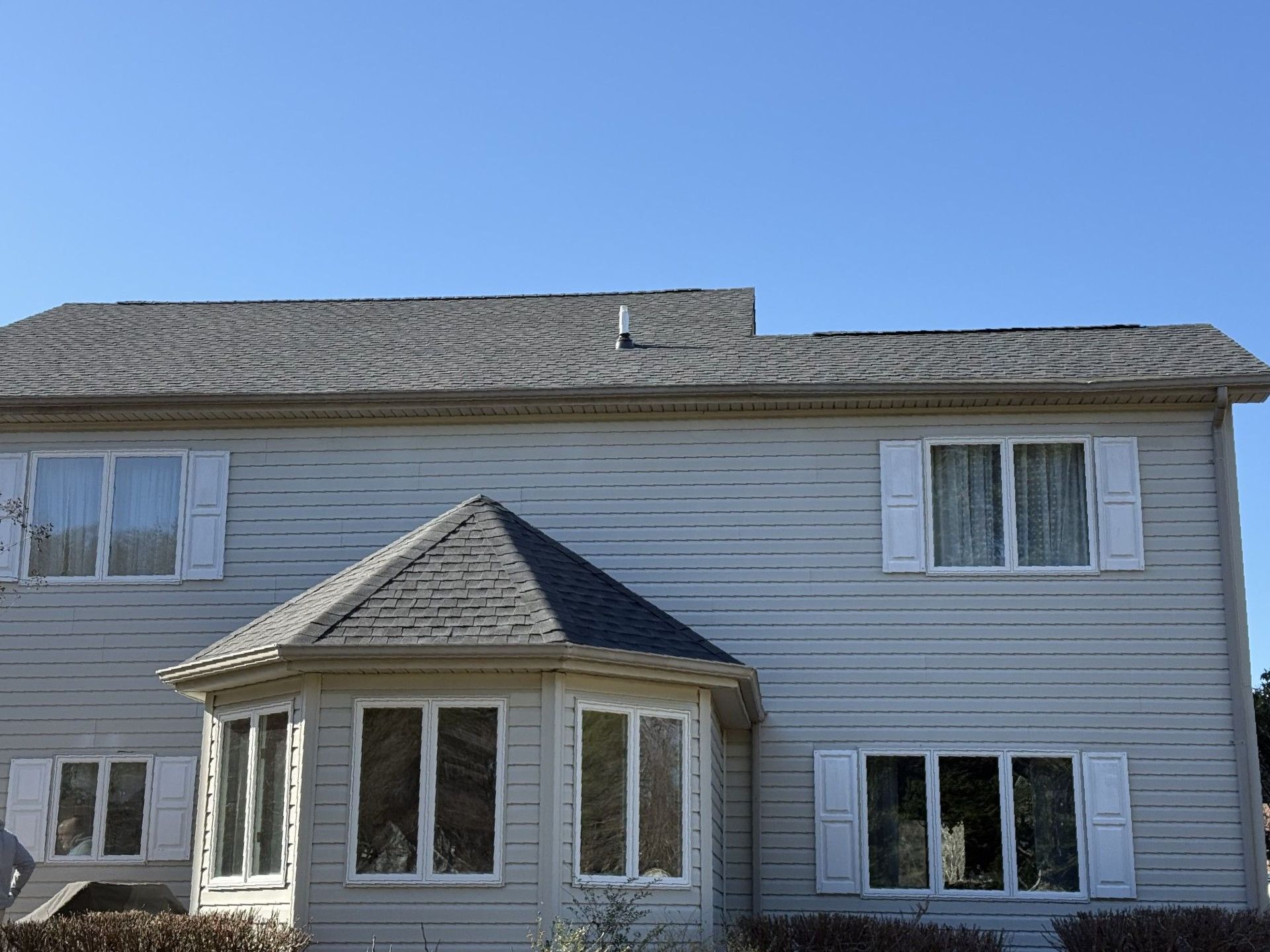 A white house with a gray roof and white shutters.