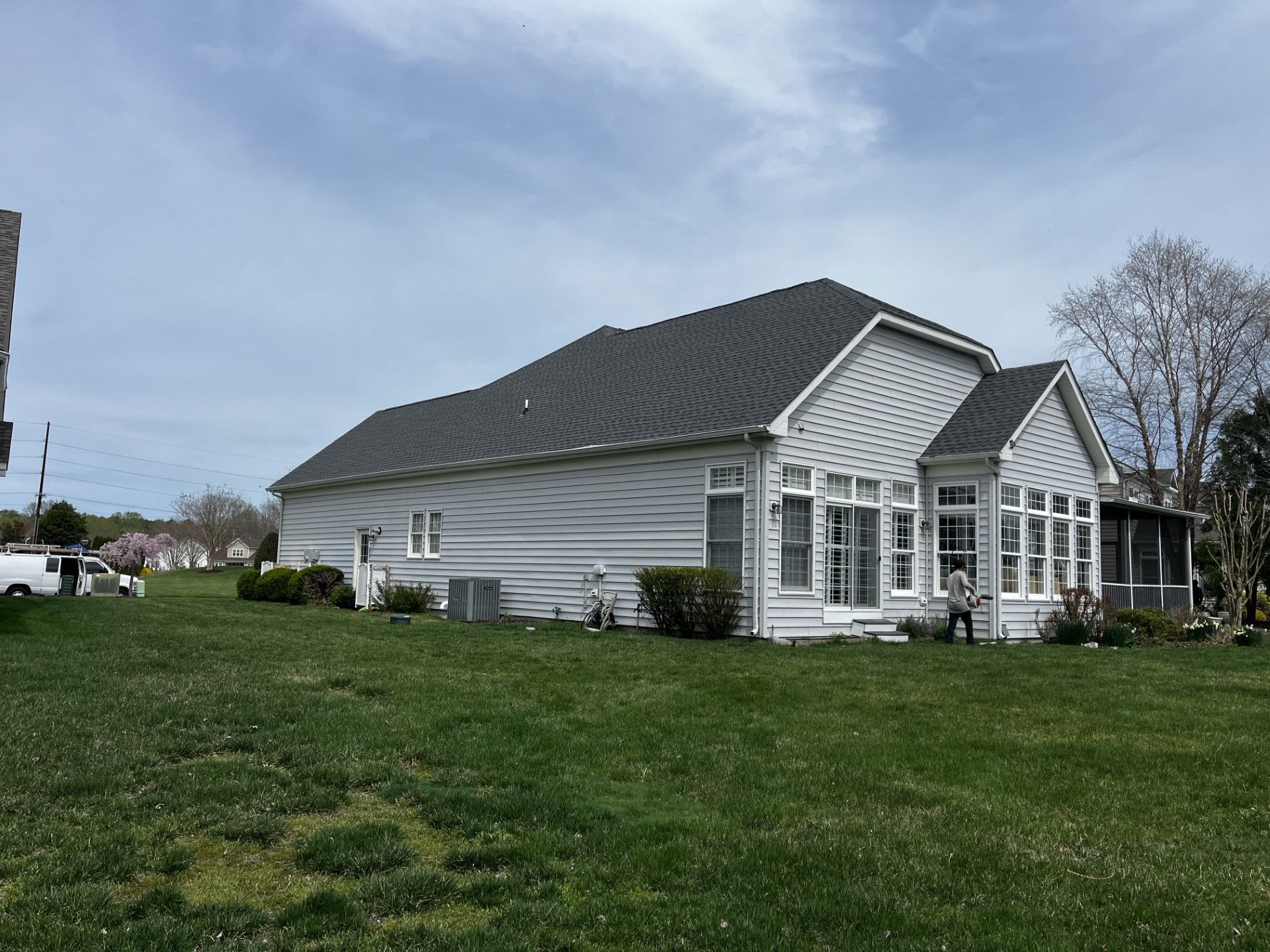 A white house with a black roof is sitting on top of a lush green field.