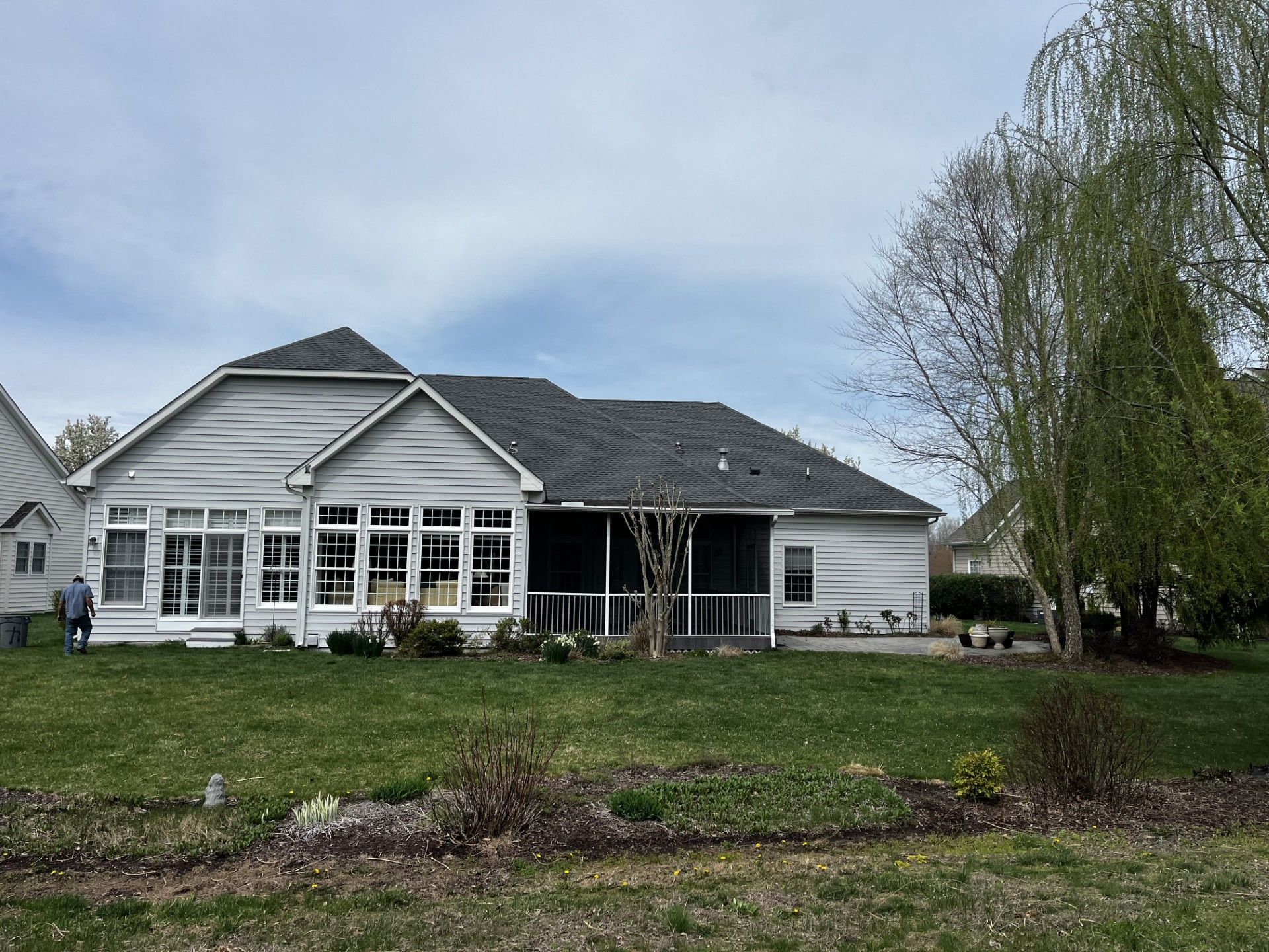 A large white house with a screened in porch and a large lawn in front of it.