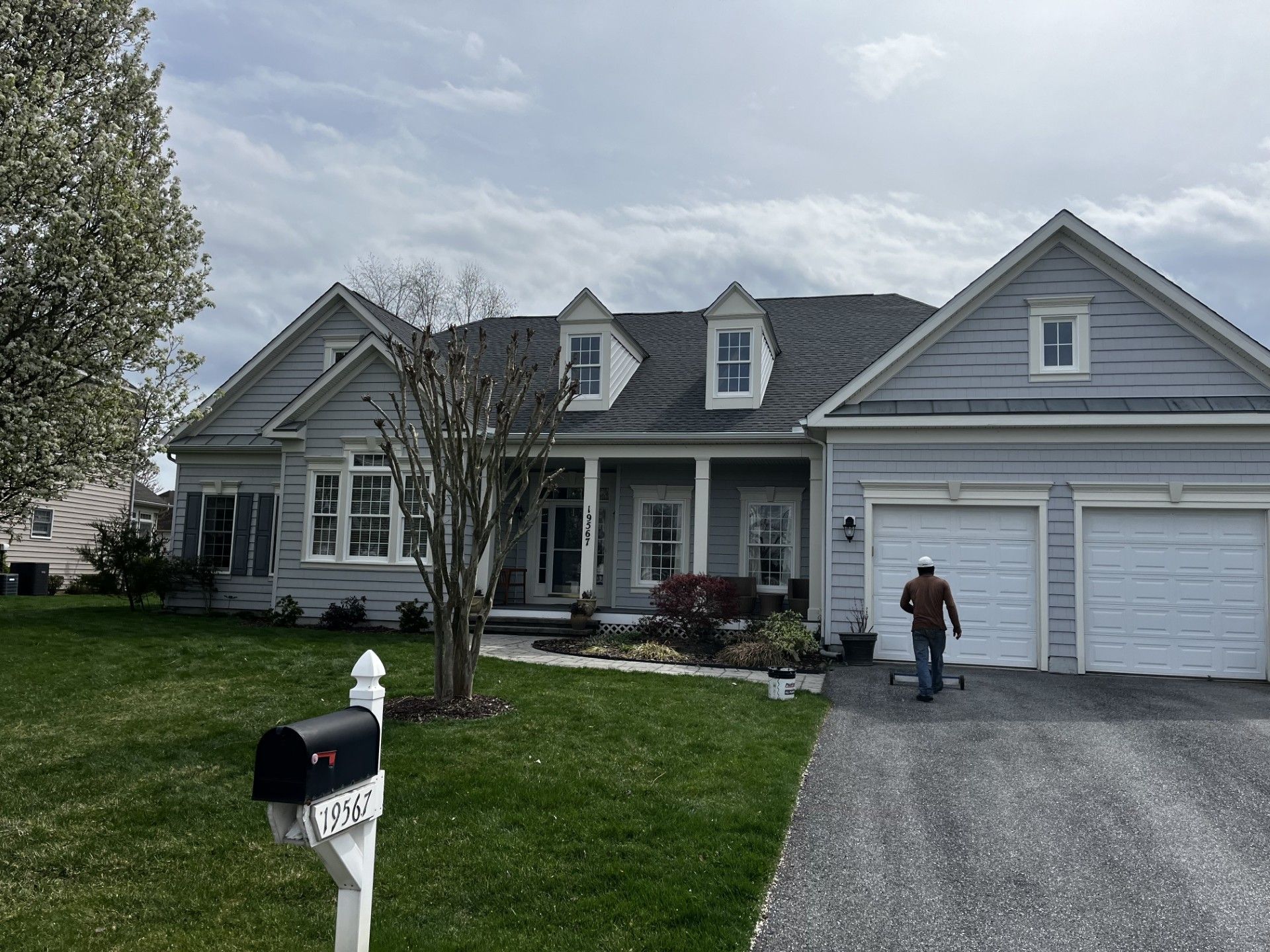 A man is standing in front of a house with a mailbox in front of it
