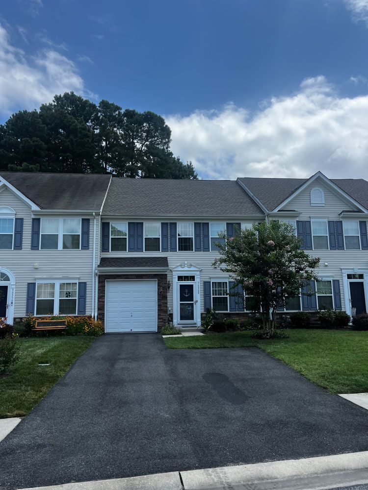 A white house with a gray roof and blue shutters