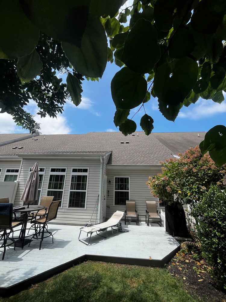 A patio with chairs and umbrellas in front of a house