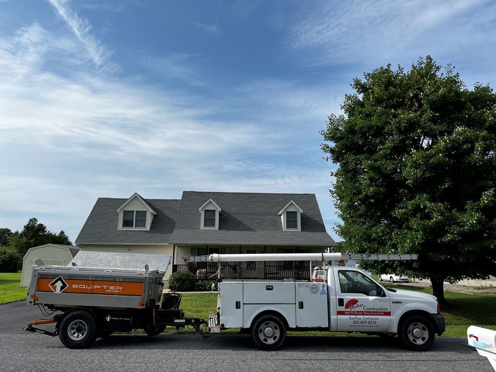 A white truck with a trailer attached is parked in front of a house