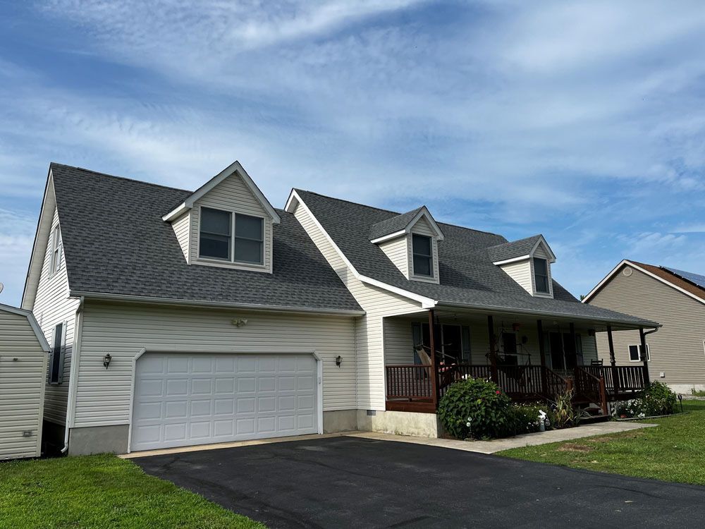 A white house with a gray roof and a white garage door