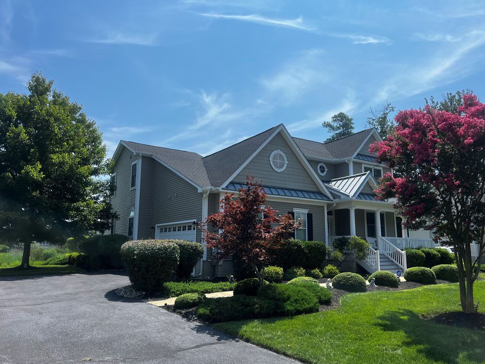 A large house with a large driveway is surrounded by trees and bushes