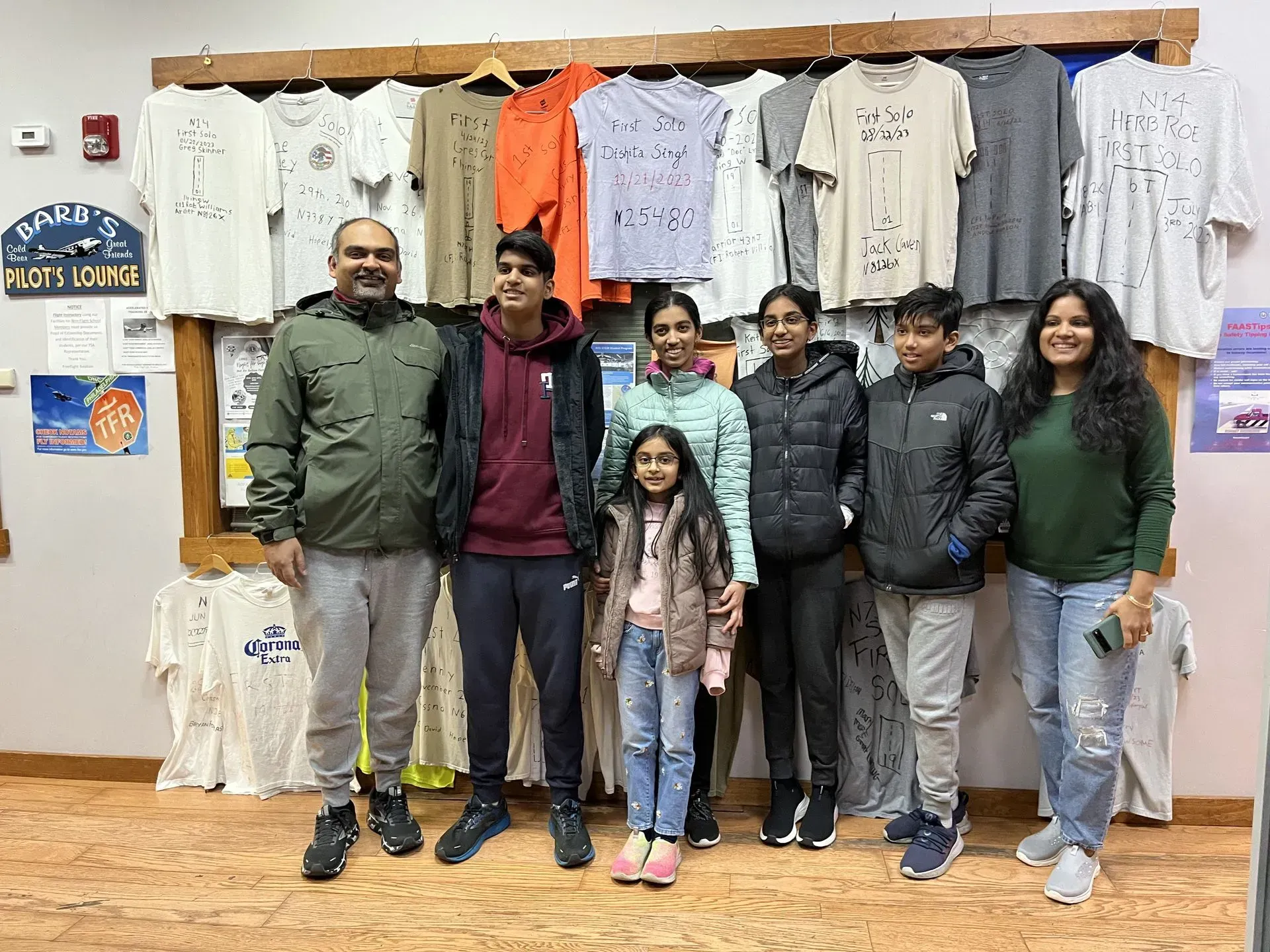 A family of seven stands in front of a wall of t-shirts.