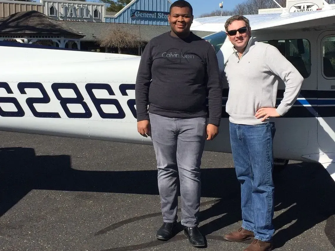 Two men stand by a small airplane with 
