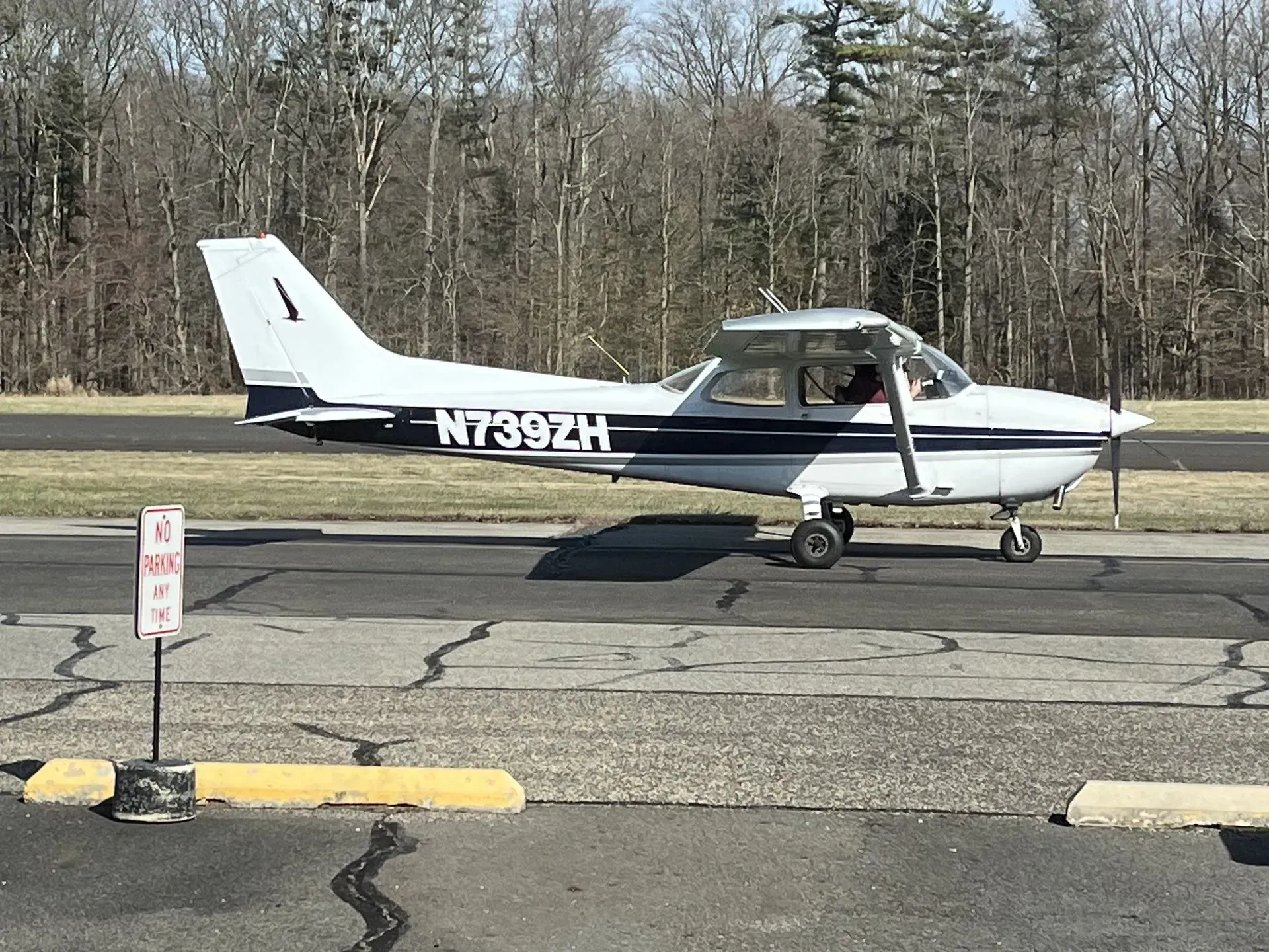 A small white and blue Cessna airplane on a runway, preparing for takeoff.