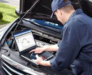 Mechanic using laptop on car for diagnostic