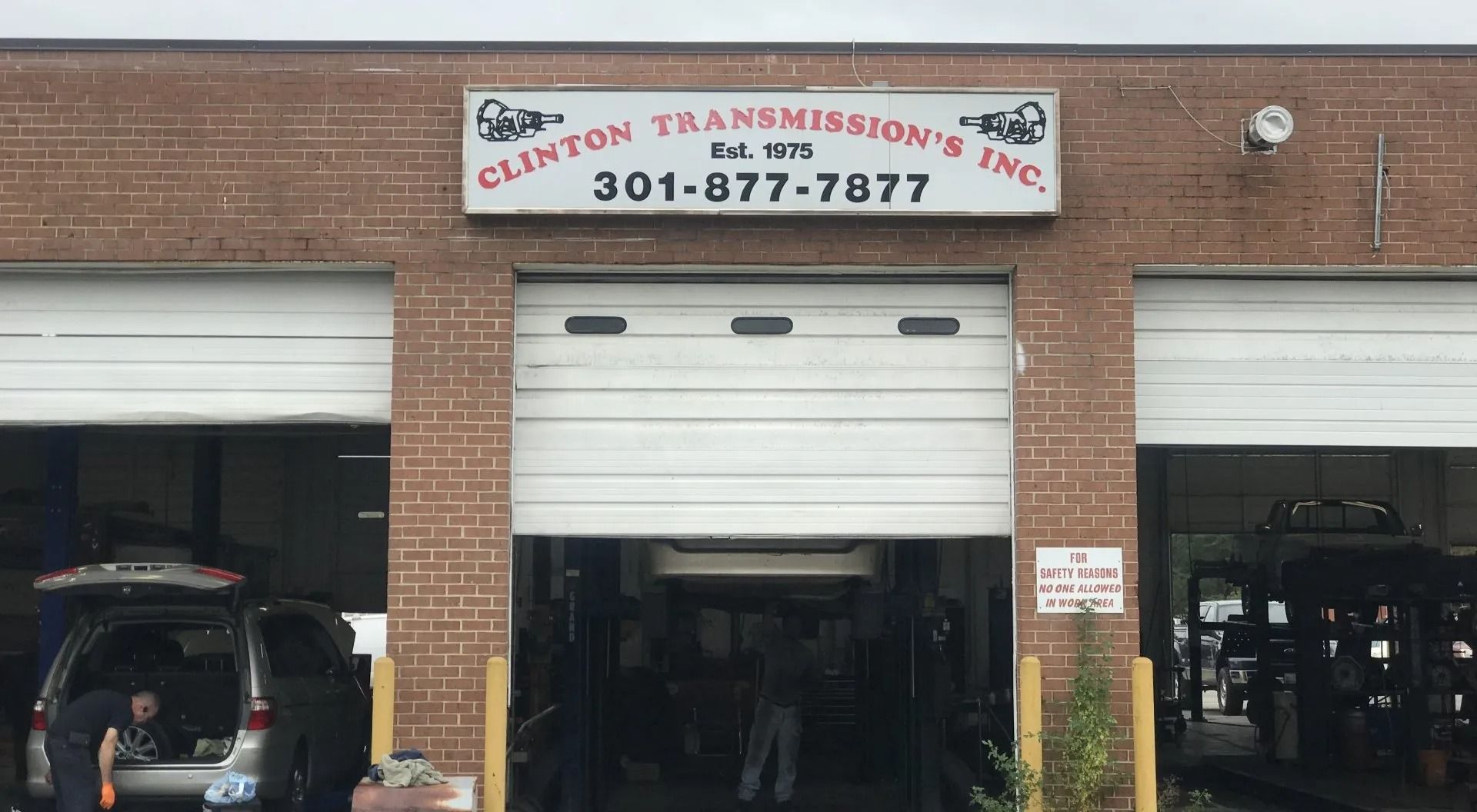 Clinton Transmissions Inc. auto repair shop with an open bay. The sign reads the name and phone number.