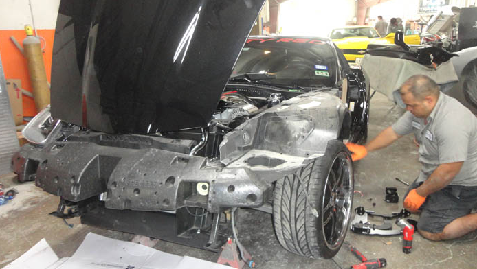 A man is working on a car with the hood open