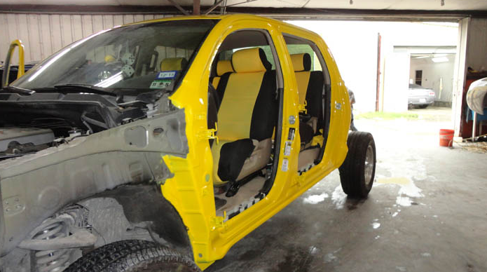 A yellow car is sitting in a garage with the doors open