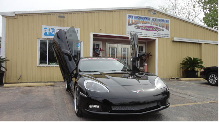 A black sports car is parked in front of a building with its doors open