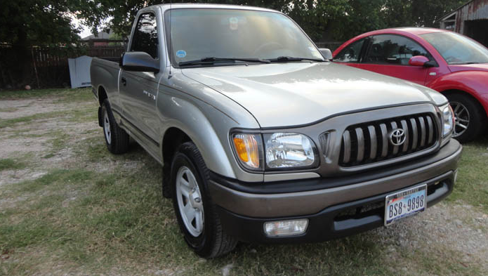 A silver truck is parked next to a red car.