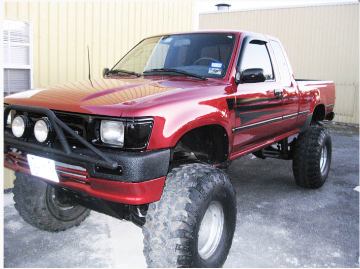 A red truck is parked in front of a building