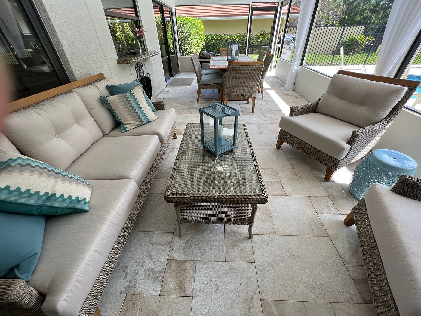 A screened porch with a couch, chairs, a table and a lantern