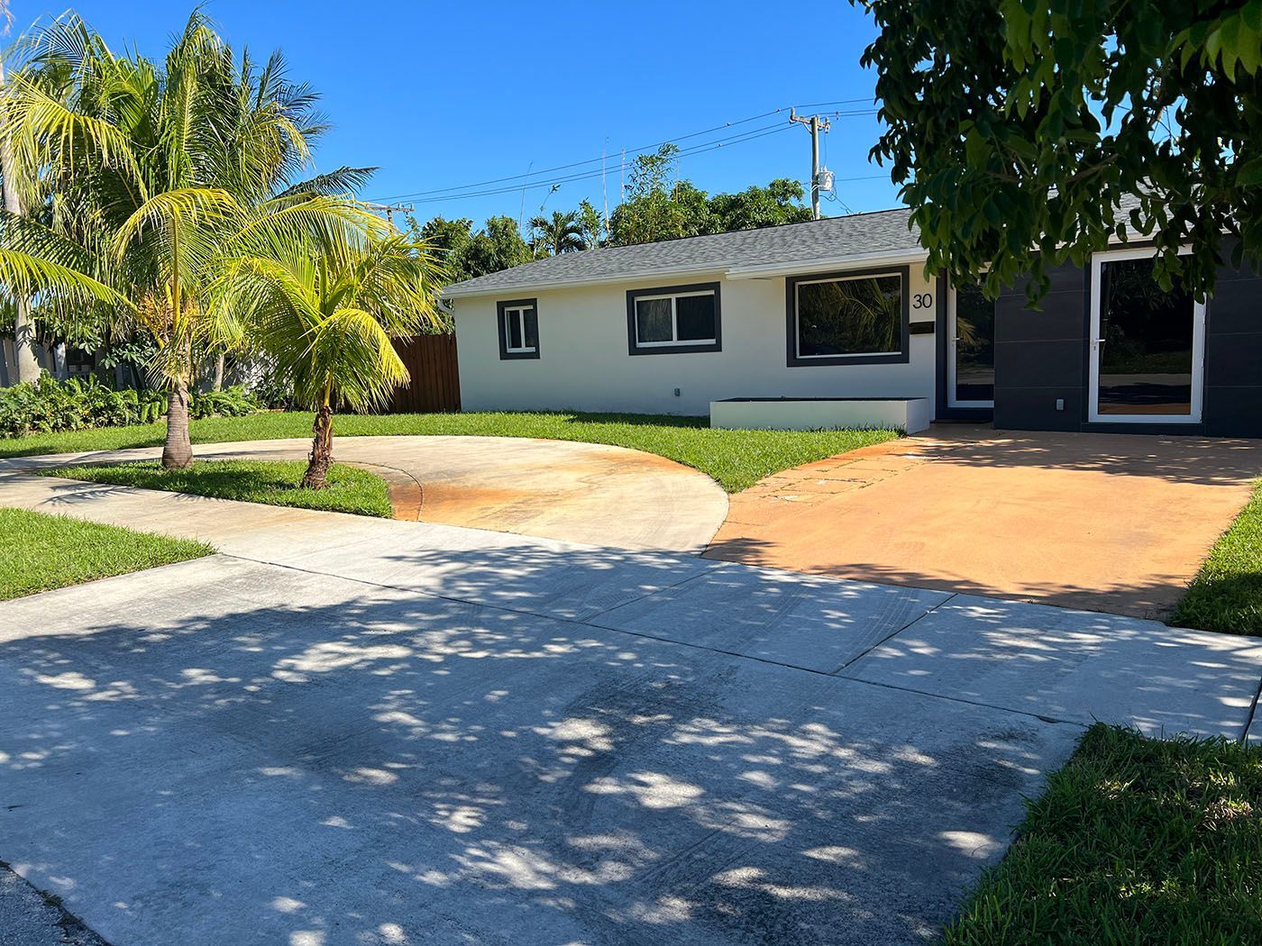 A white house with a driveway and trees in front of it