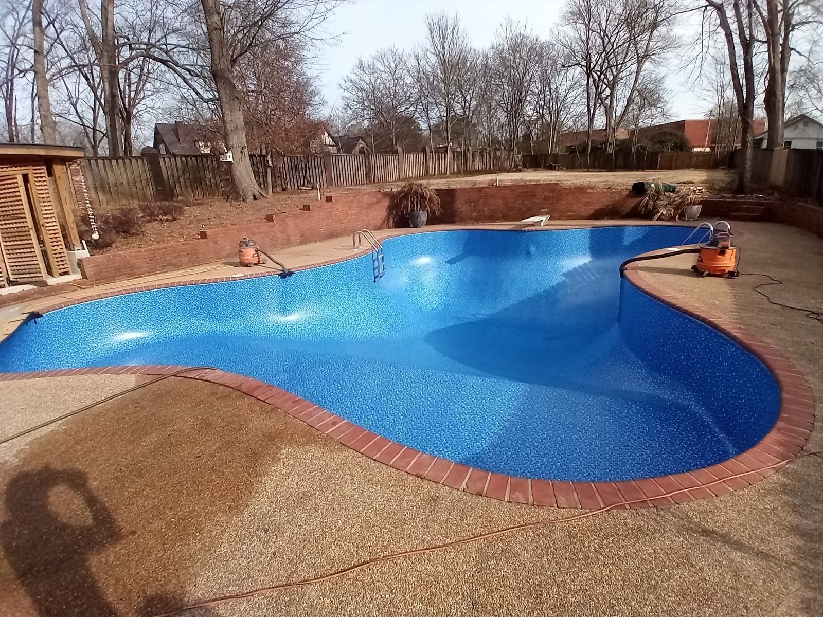 A large blue swimming pool is being built in a backyard.