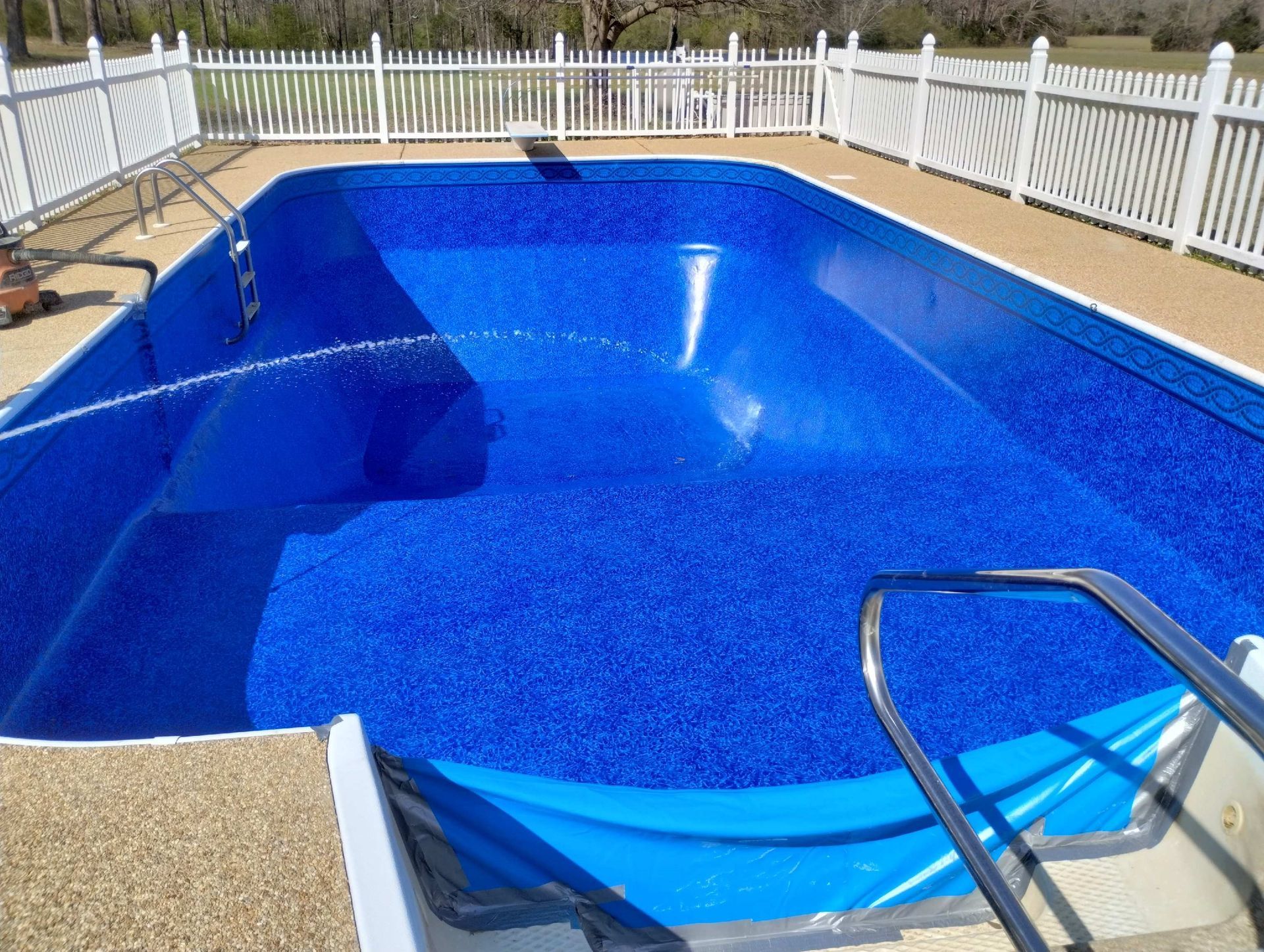A large blue swimming pool with a white fence around it.