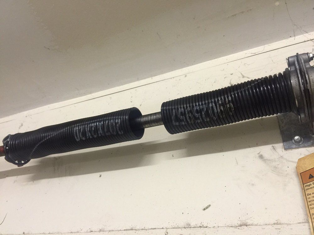 A close up of a black spring on a white surface.