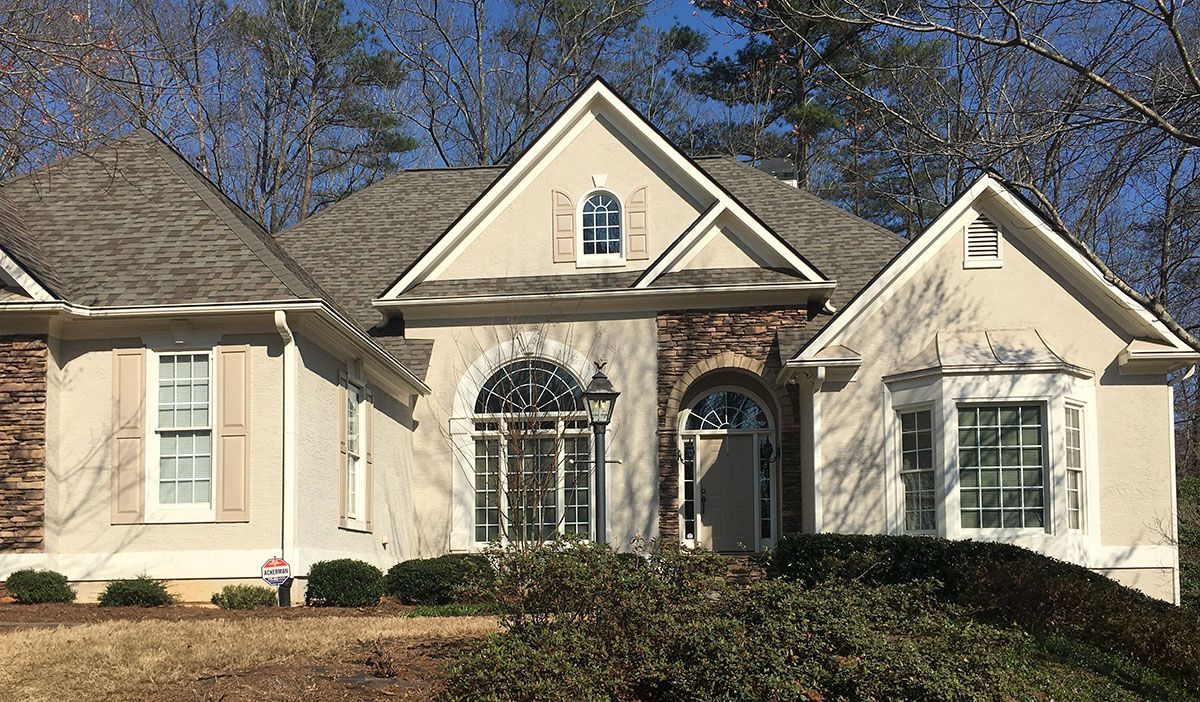 A large white house with a gray roof is sitting on top of a hill.