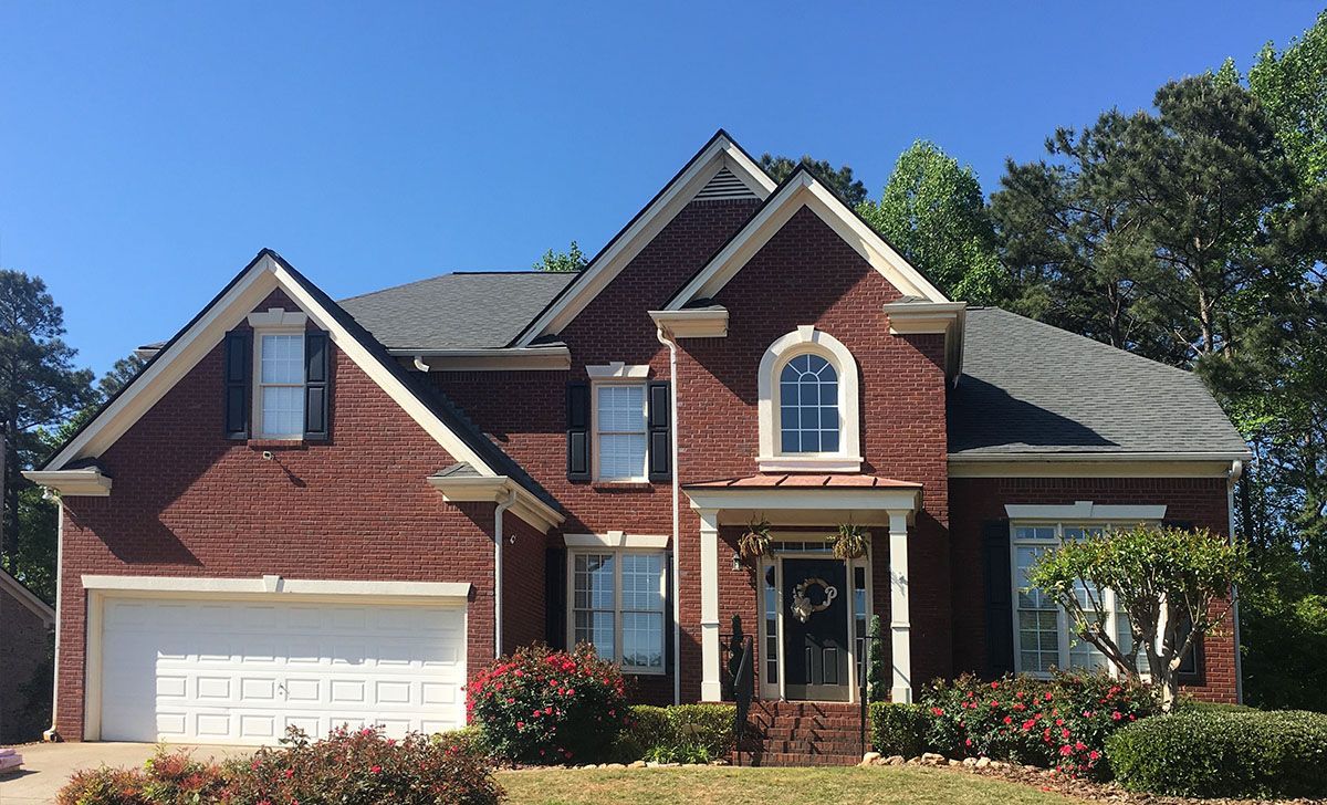 A large red brick house with a white garage door and a gray roof.