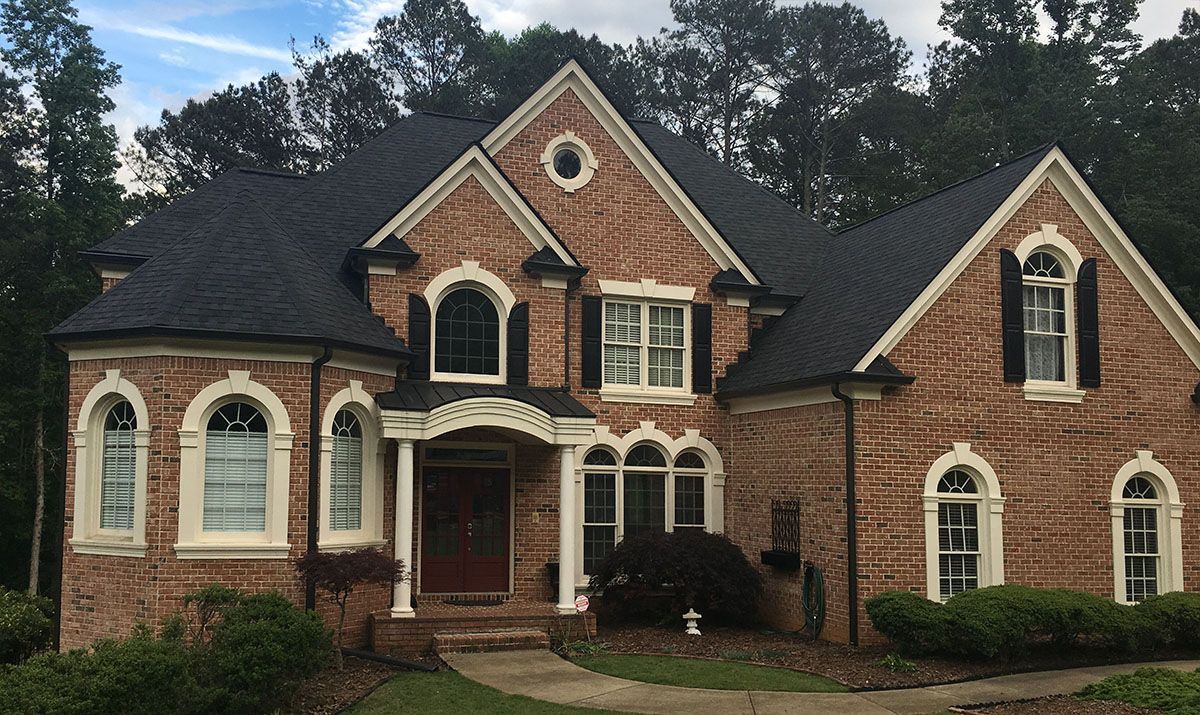 A large brick house with a black roof and arched windows.