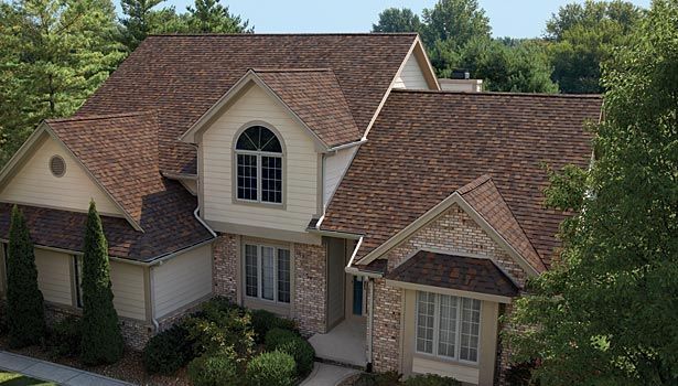 An aerial view of a large house with a brown roof surrounded by trees.