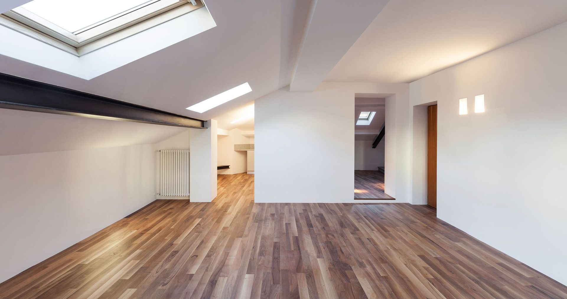 An empty room with wooden floors and a skylight in the ceiling.