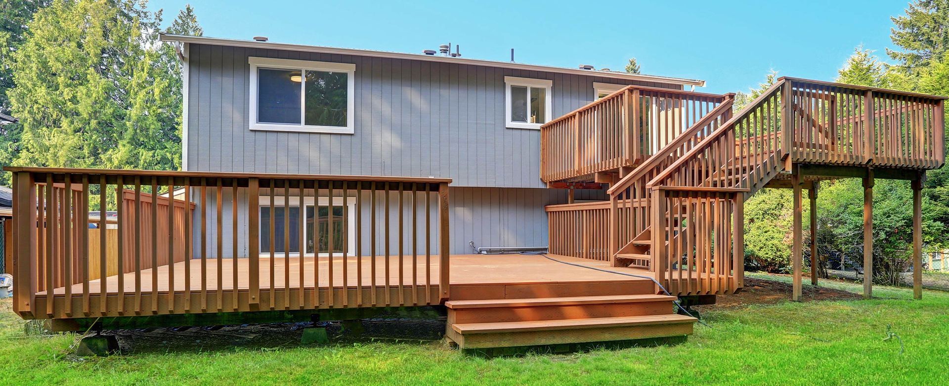 The back of a house with a large wooden deck and stairs.