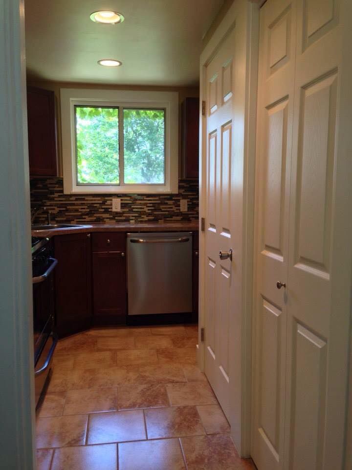 A kitchen with a stainless steel dishwasher and a window.
