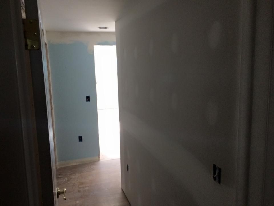 A hallway with blue walls and a door in a house under construction.