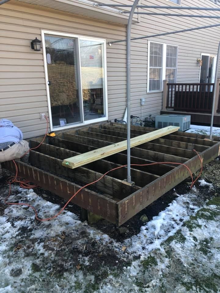 A wooden deck is being built in the snow in front of a house.