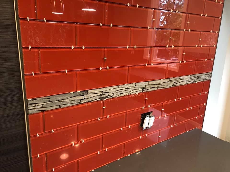 A wall with red tiles and a stone border is being built.