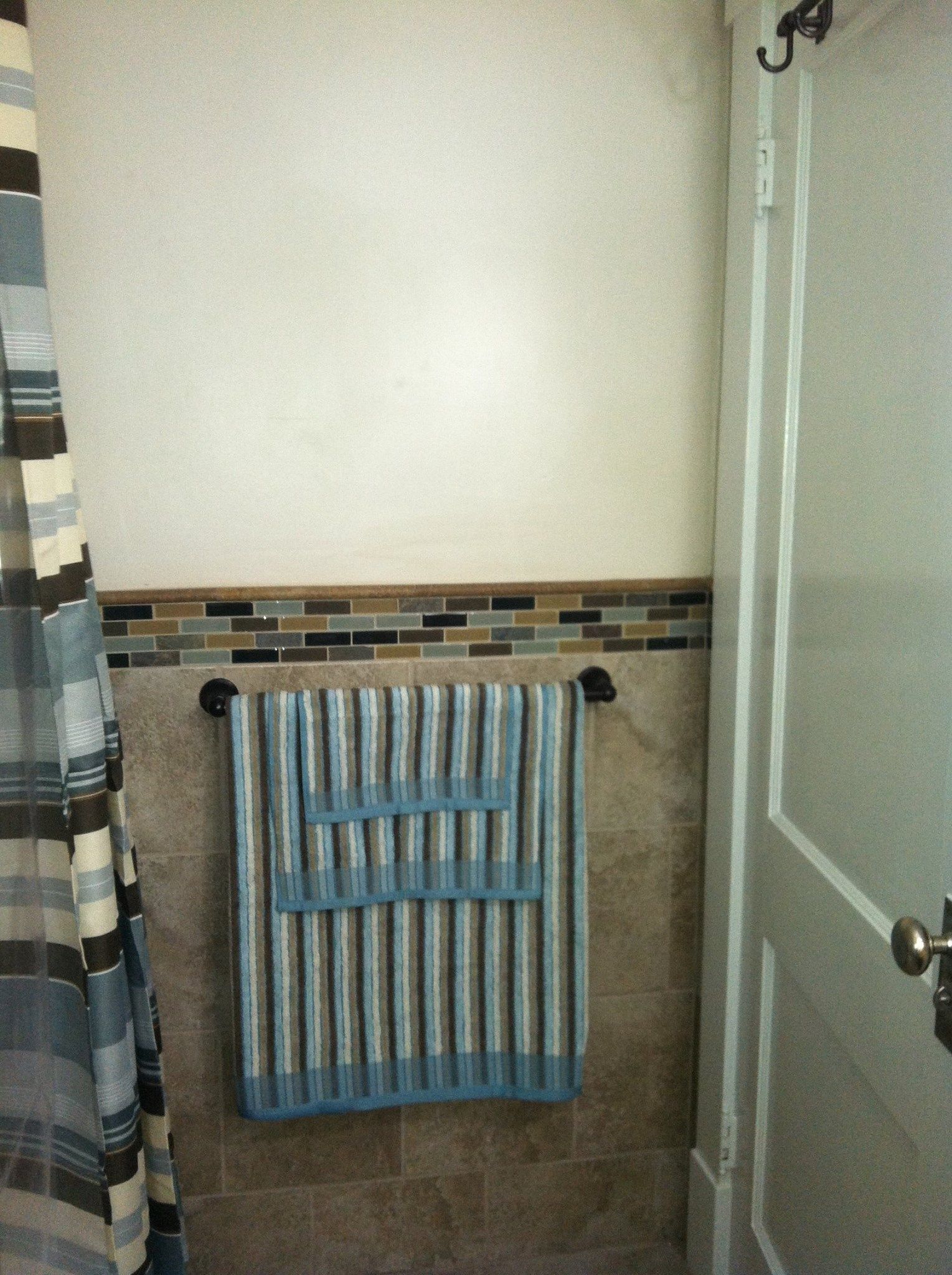 A bathroom with a shower curtain and a towel rack