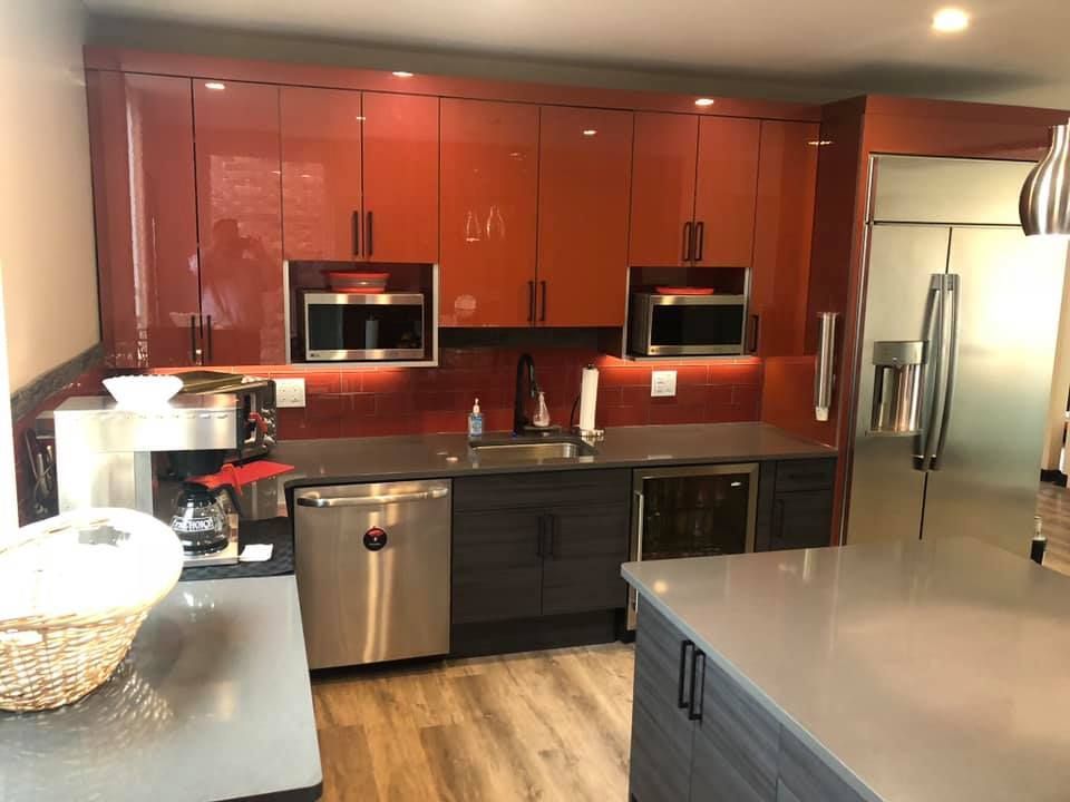 A kitchen with red cabinets and stainless steel appliances.