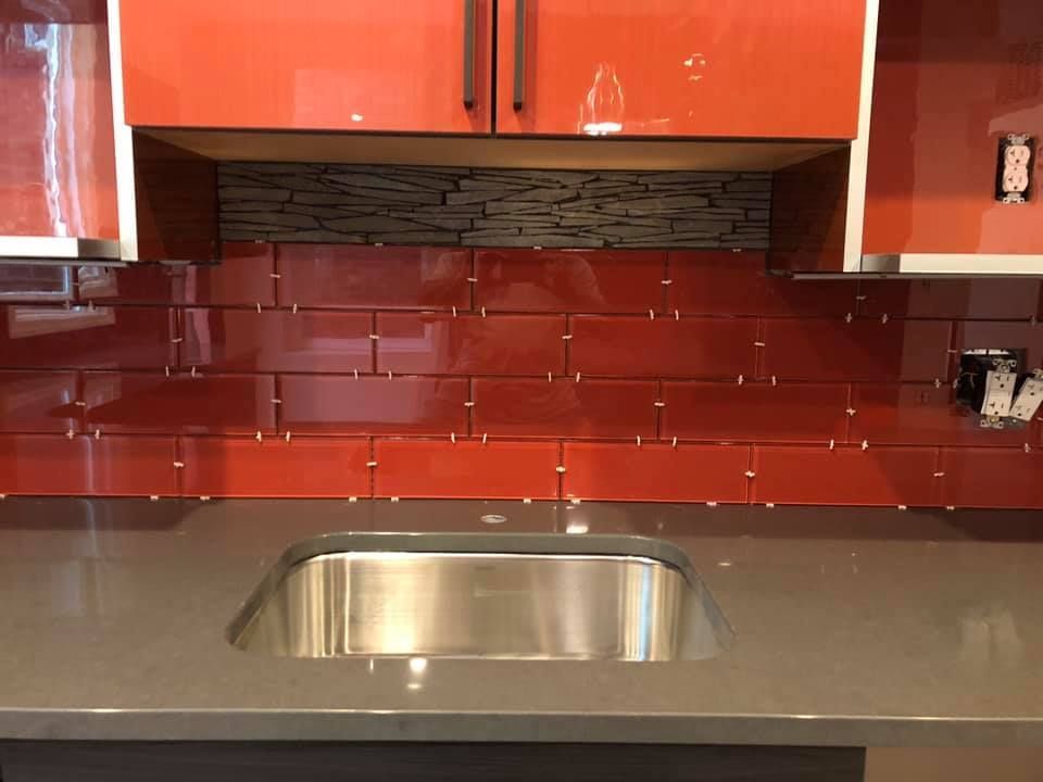 A kitchen with red tiles and a stainless steel sink