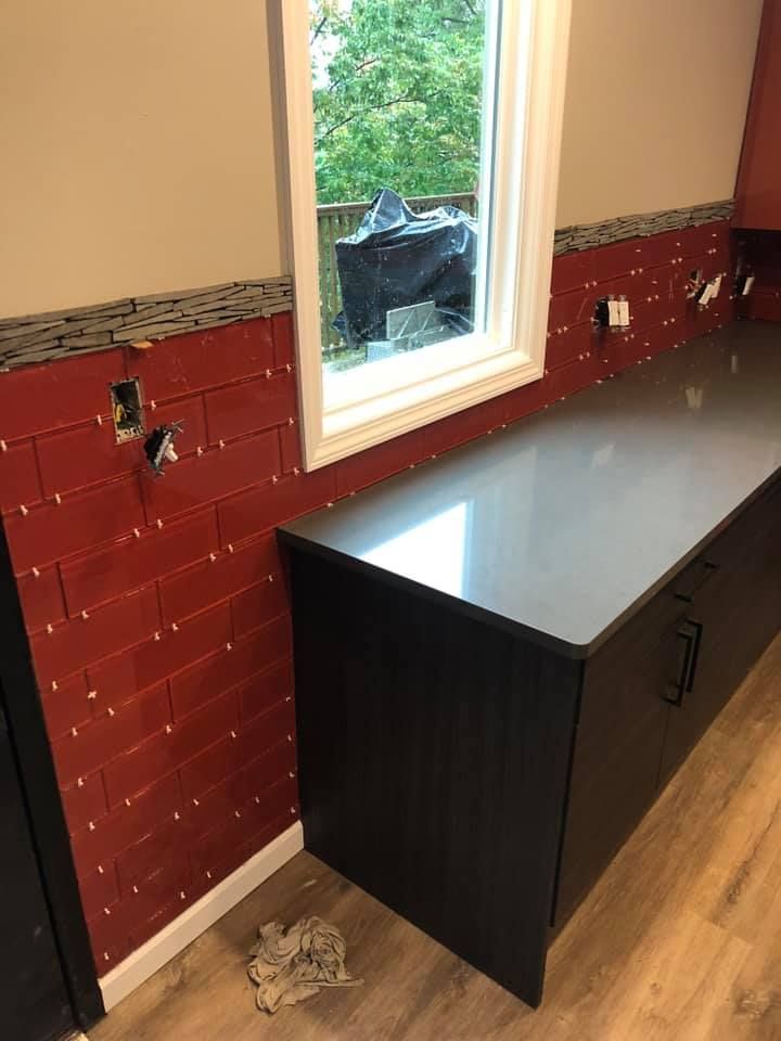 A kitchen with red brick walls and a black counter top.