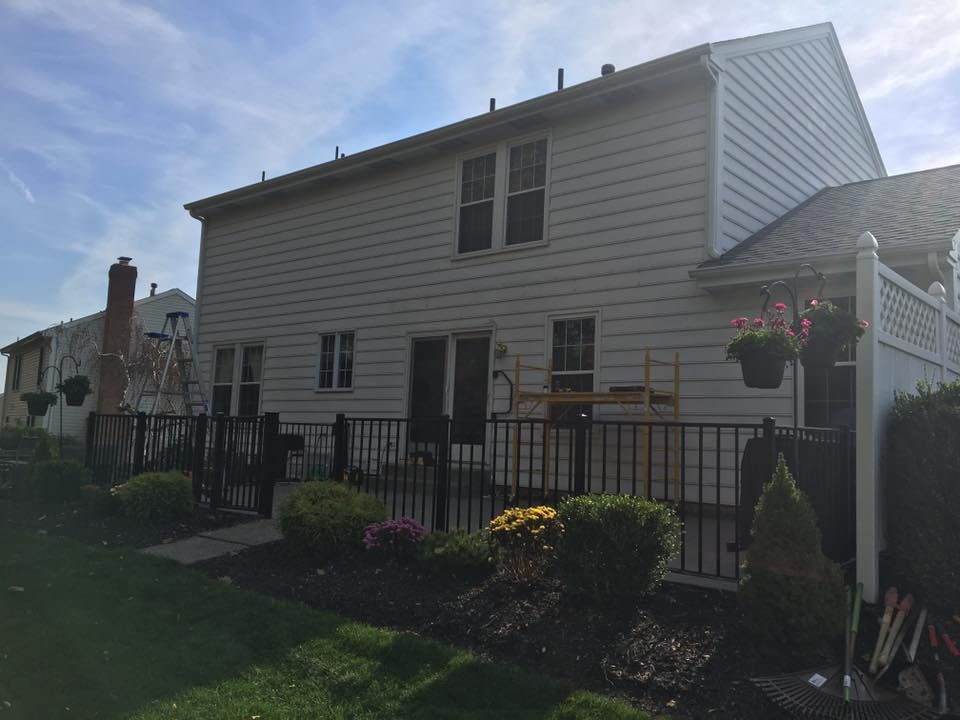 The back of a house with a fence and flowers in front of it.