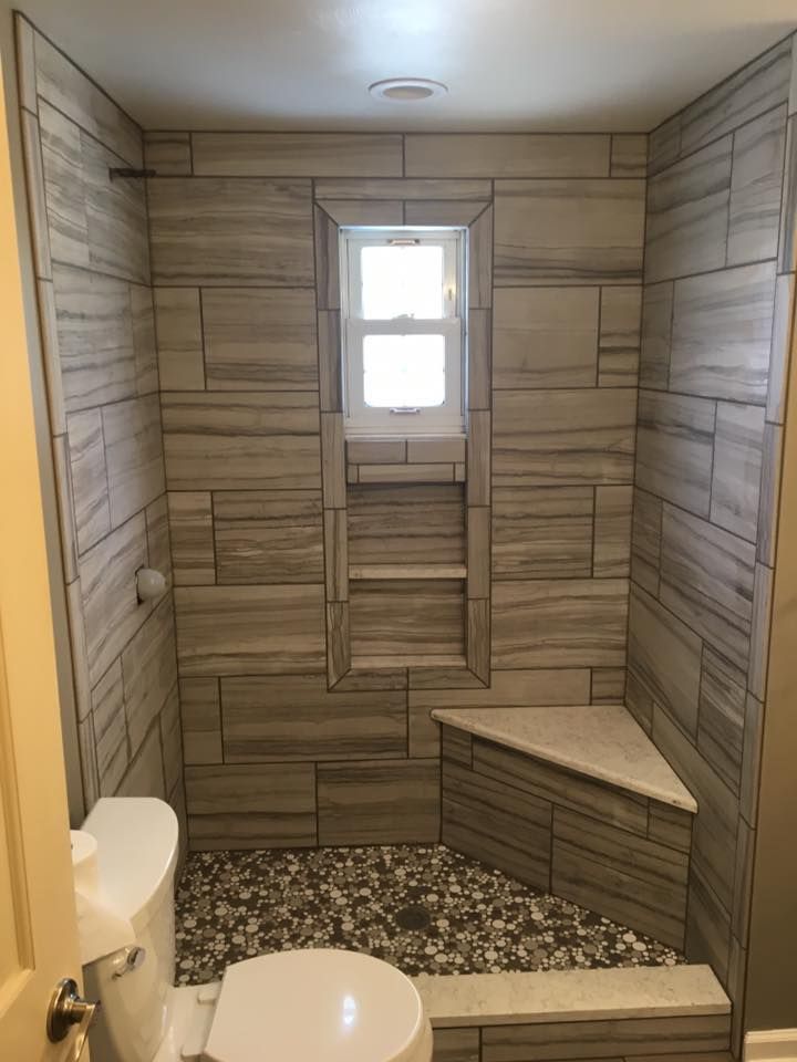 A bathroom with a toilet , shower , and window.
